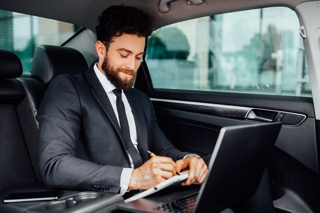 Business executive working on a laptop in the quiet cabin of an executive car service in Vancouver.